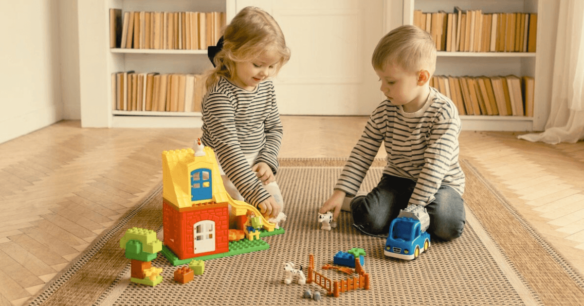 3-year-olds playing on a rug with pretend play toys