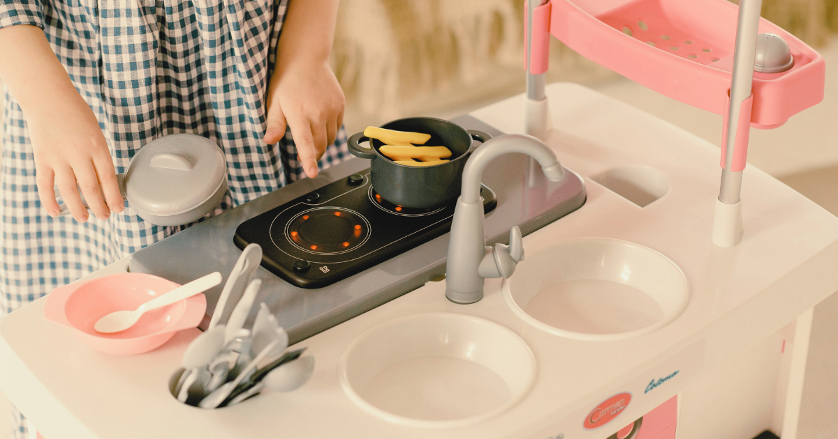 Child playing with pretend stove feature on a play kitchen