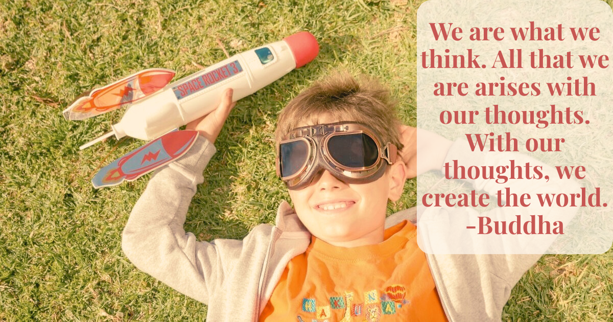 make-believe play for 7 and 8 year olds. 7 year old boy laying on grass with goggles on, holding a toy rocket.