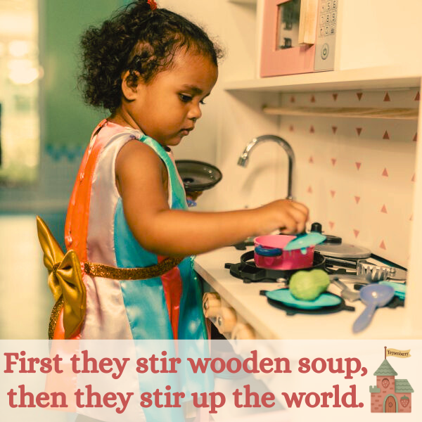 A toddler child making pretend soup on a wooden play kitchen