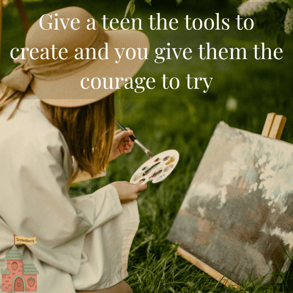 teen girl painting on canvas while sitting in the grass—paint sets are awesome gifts for creative teens